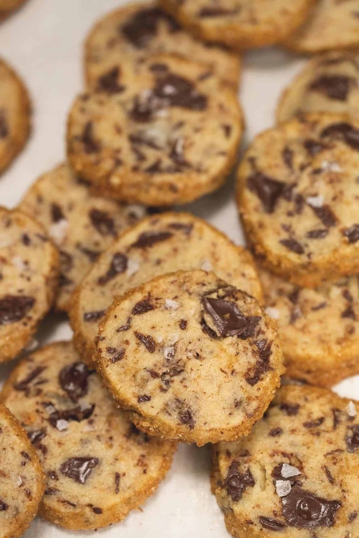 chocolate chip cookies are arranged on a white counter top, ready to be eaten and served