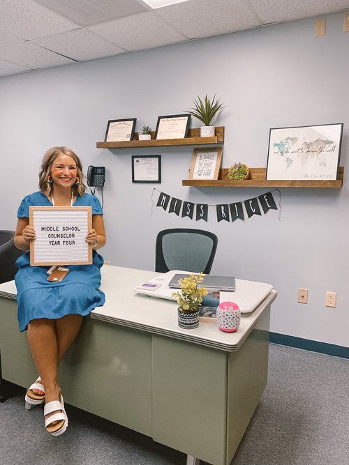 a woman sitting on a desk holding up a sign