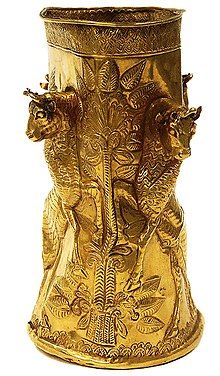 an ornate gold vase with elephants on it