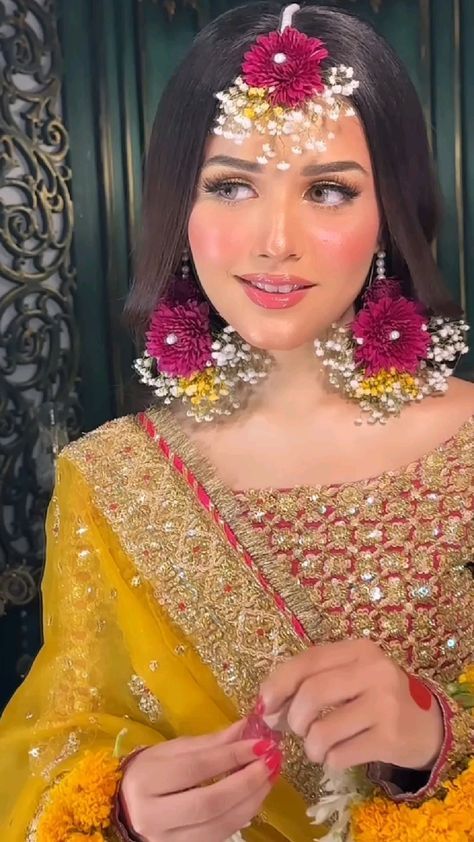 a woman with flowers in her hair is wearing a yellow and red outfit while she looks at the camera