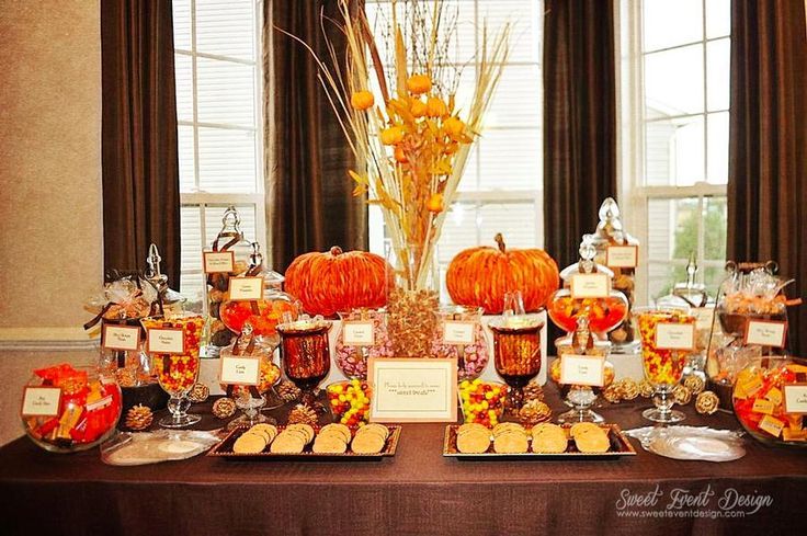 a table topped with lots of candy and candies next to two large pumpkins