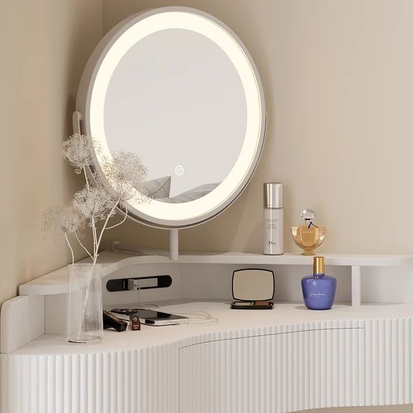 a round mirror sitting on top of a white shelf next to a vase with flowers