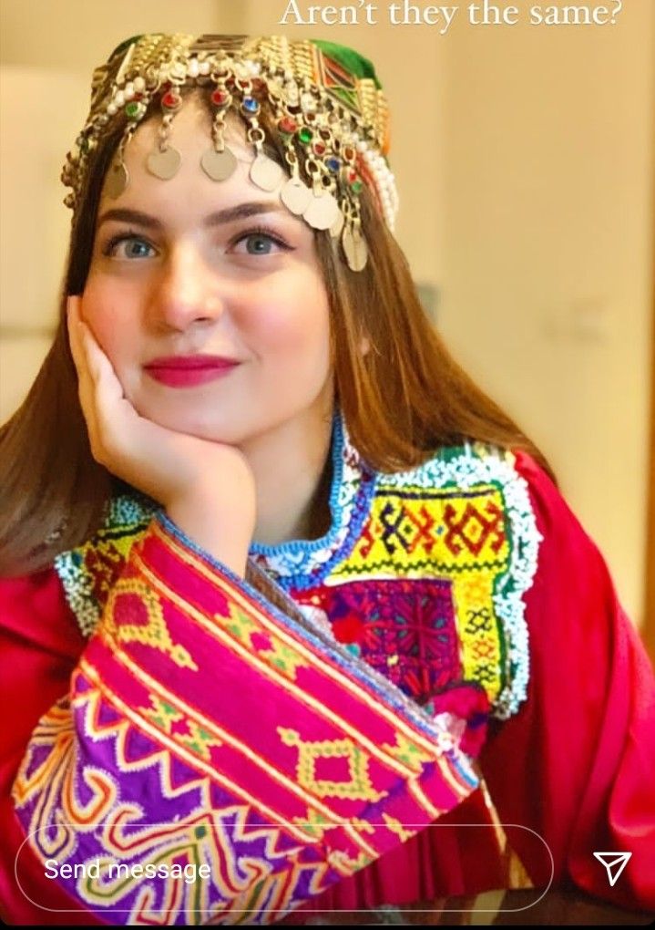 a woman with long hair wearing a colorful headdress and holding her hand on her chin