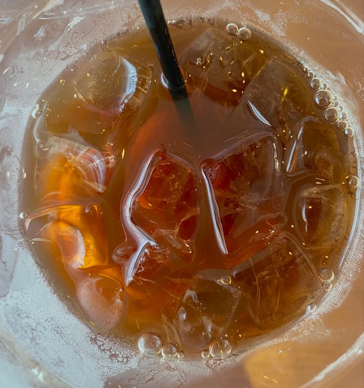 ice cubes and orange juice in a bowl with a black plastic spoon on top