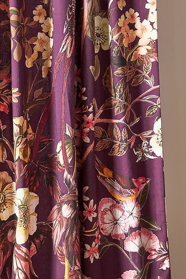 a purple floral print curtain hanging from a window