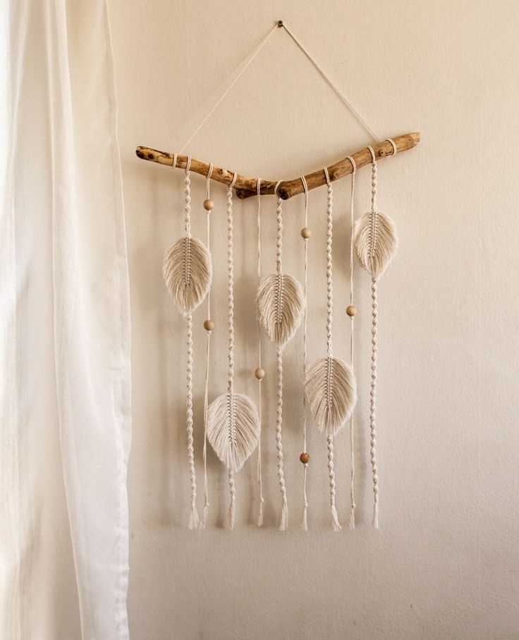 a wall hanging made out of shells and rope with beads attached to the strings,