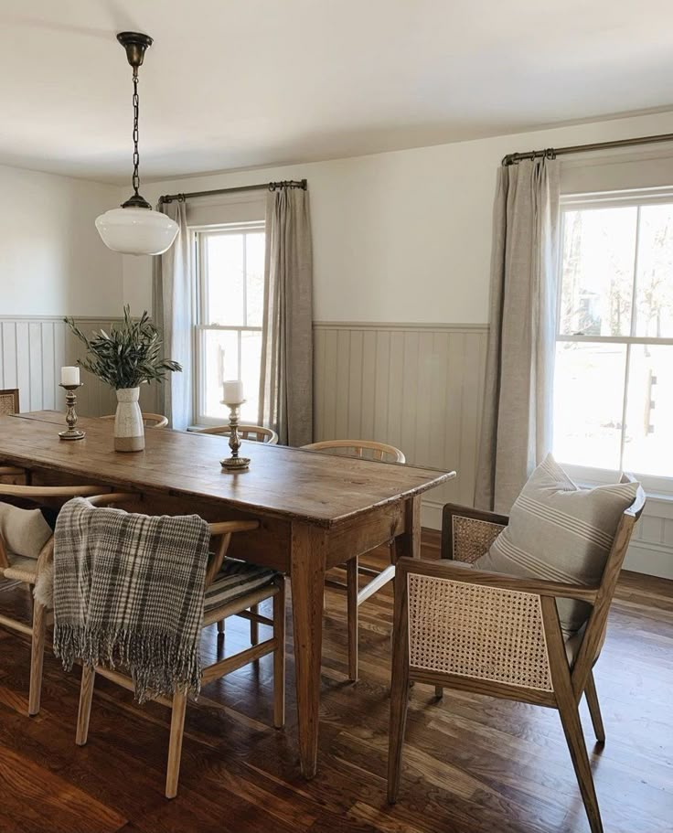 a dining room table and chairs in front of two windows