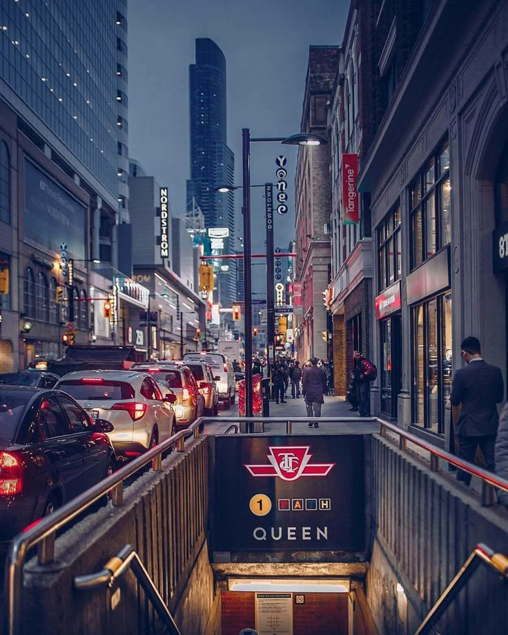 a city street filled with lots of traffic next to tall buildings and people walking on the sidewalk