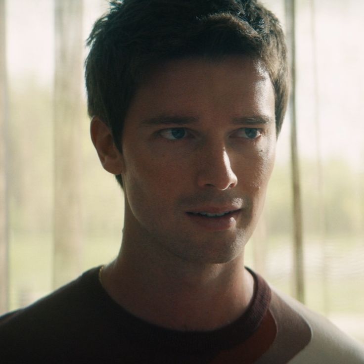 a close up of a person wearing a brown shirt and looking at the camera with a serious look on his face