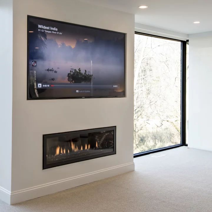 a large flat screen tv mounted to the side of a wall next to a fire place