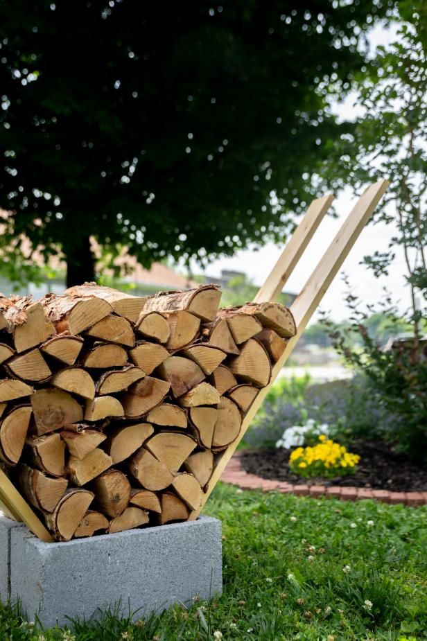 a pile of wood sitting on top of a cement block in the middle of grass