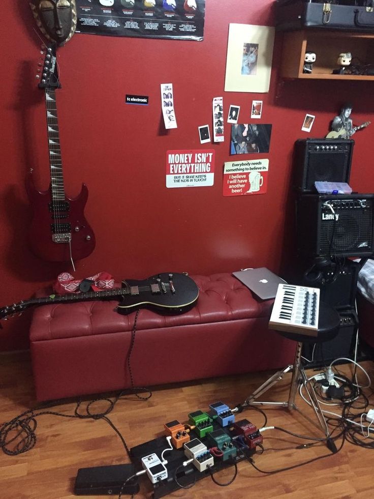 a room with red walls, guitars and other musical equipment on the floor in front of it