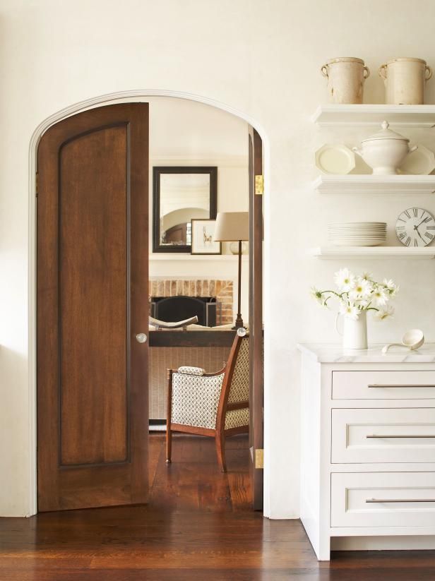 an open door leading to a living room with white walls and wooden flooring on the other side