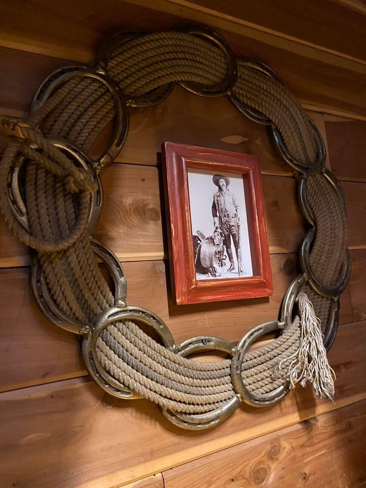 an old photo hangs on the wall next to a roped wreath and framed photograph