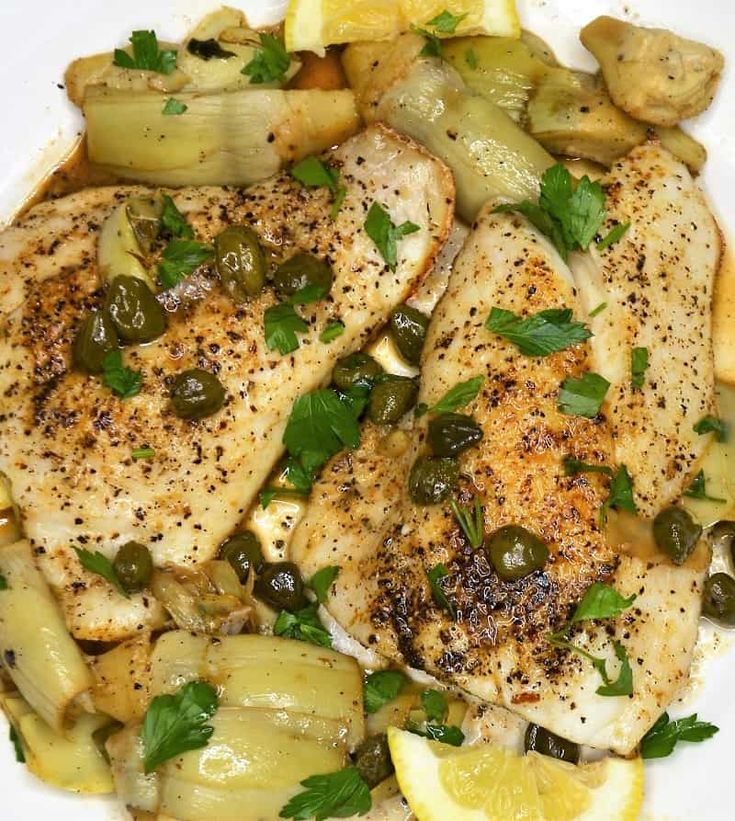 chicken with lemon, olives and onions on a white plate topped with parsley