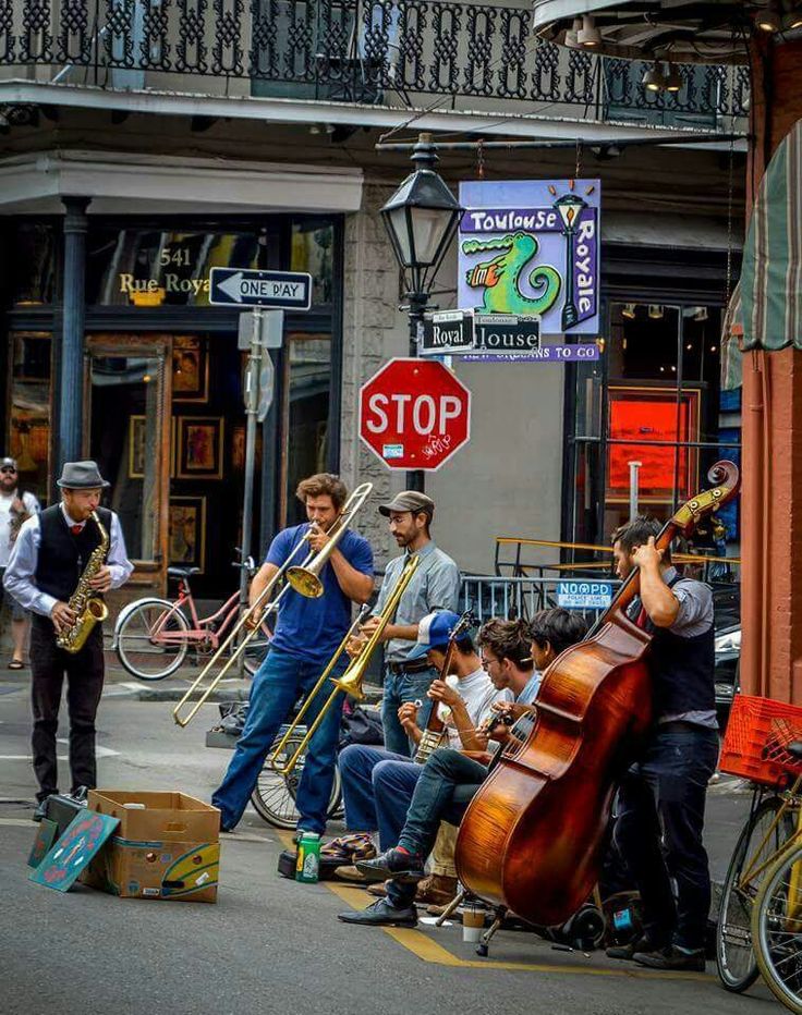 a group of people playing musical instruments on the street in front of a stop sign