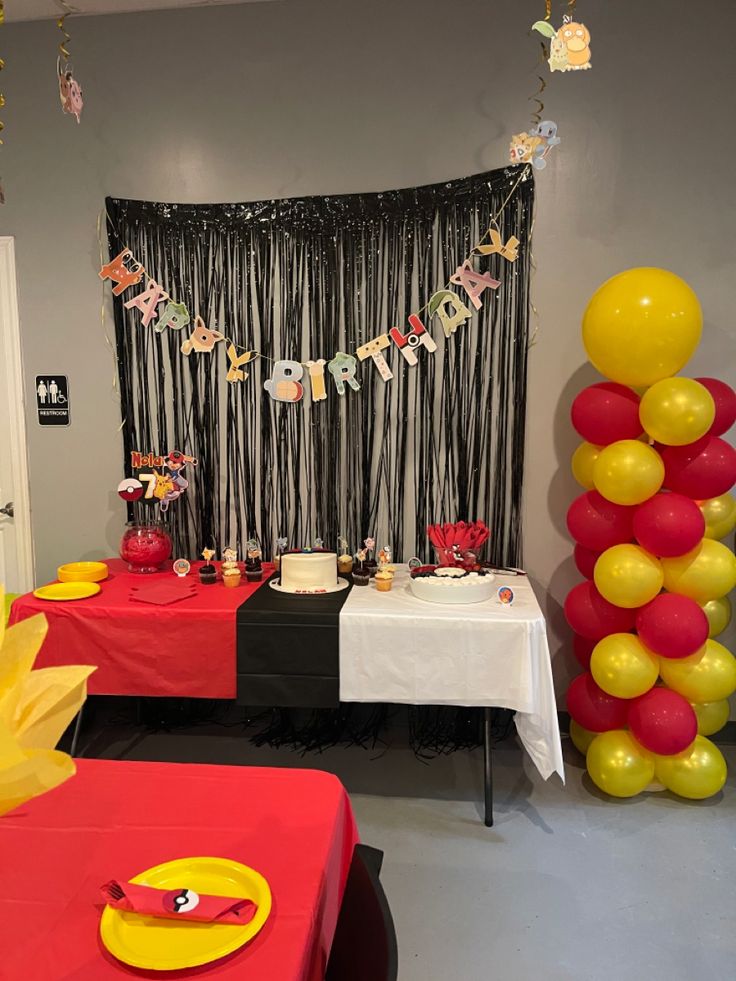 a party with balloons and streamers hanging from the ceiling, table cloths on the tables