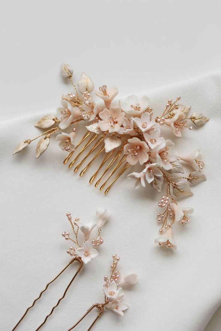 three hair combs with flowers and leaves on top of a white cloth covered table