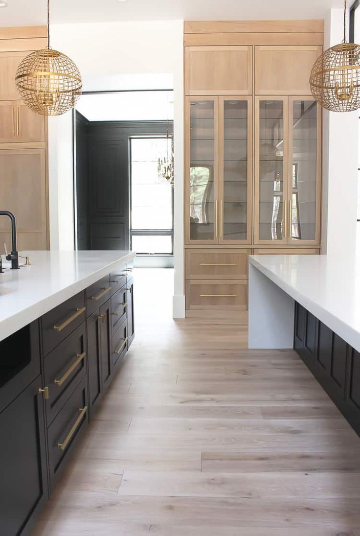 an empty kitchen with black cabinets and white counter tops is seen in this image from the hallway