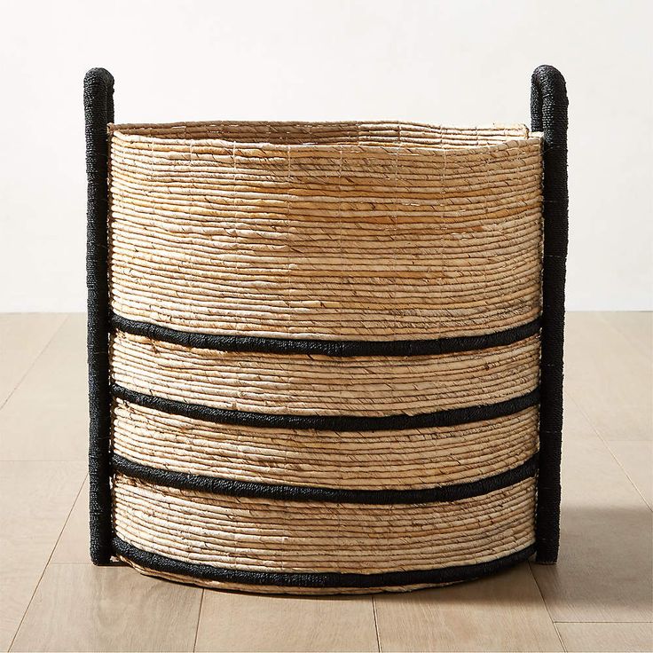 a basket with black handles on top of a wooden floor