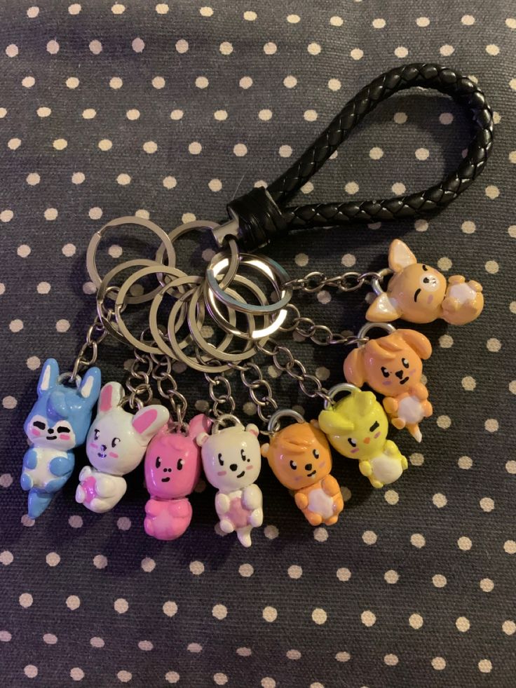 the keychain has five small cartoon animals on it's side and is attached to a black leather cord