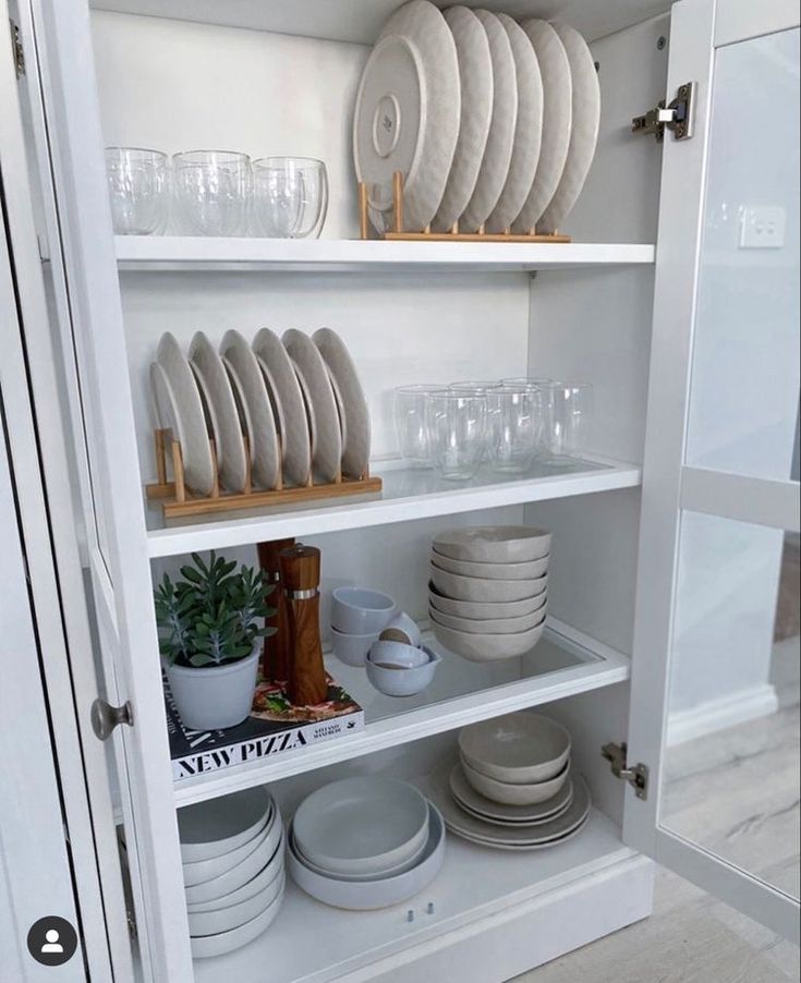 white dishes and plates are on shelves in the kitchen