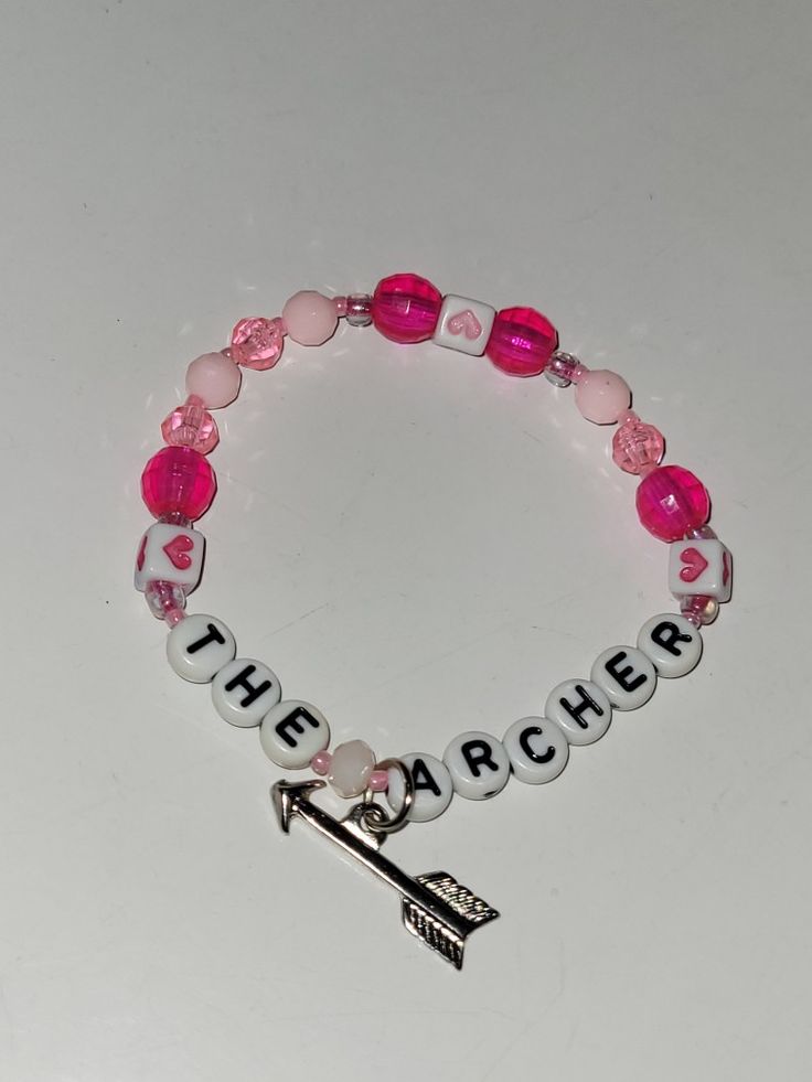 a pink and white beaded bracelet with an arrow charm on it that says the archer