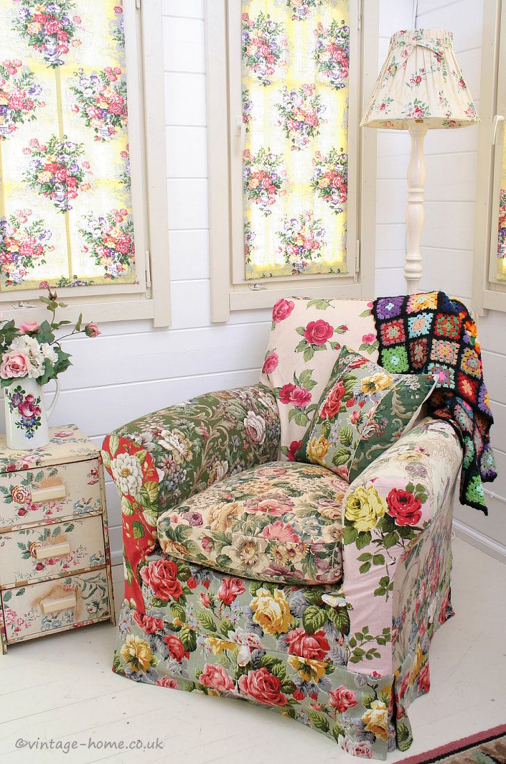 a living room filled with furniture and flowers on the walls next to two small windows