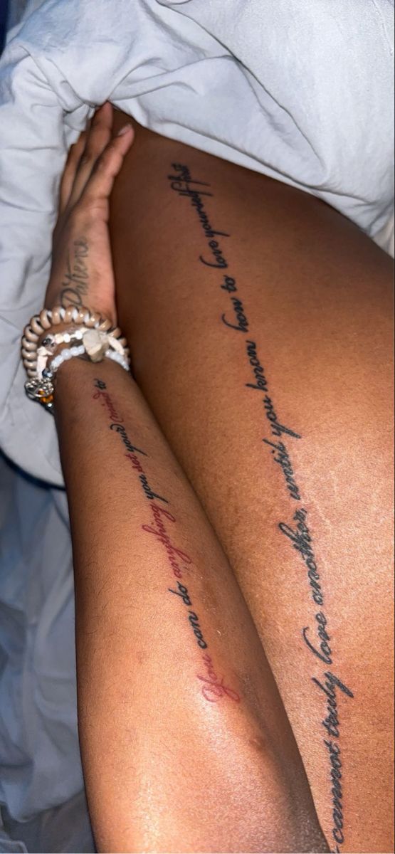 a woman's leg with writing on it and her hand resting on the bed