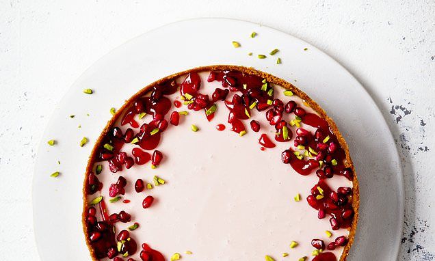 a white plate topped with a cheesecake covered in pomegranate and seeds