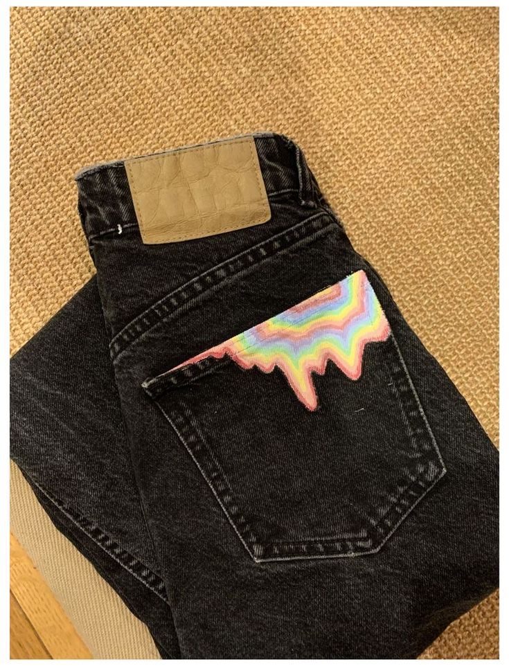 a pair of black jeans with a rainbow sticker in the pocket on top of it