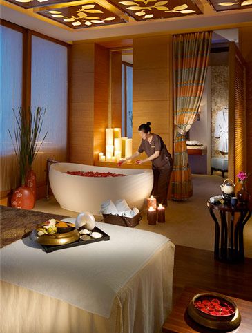 a woman in a spa setting with candles on the side of the bathtub and other items