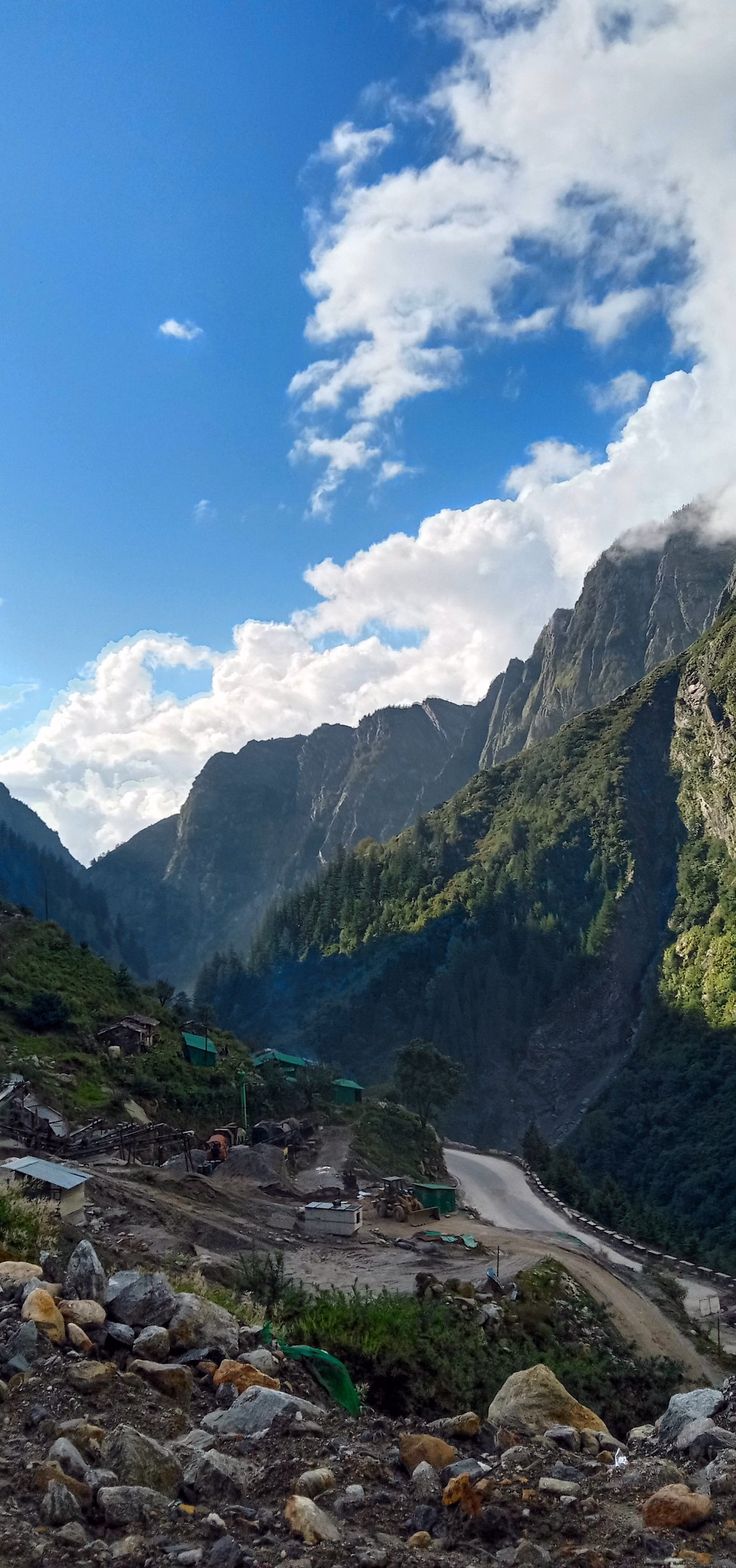 there are many rocks and gravel on the side of this mountain road with mountains in the background