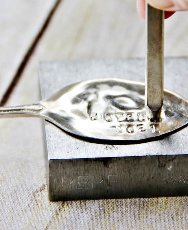 a person is using a metal tool to make a stamp on a piece of wood