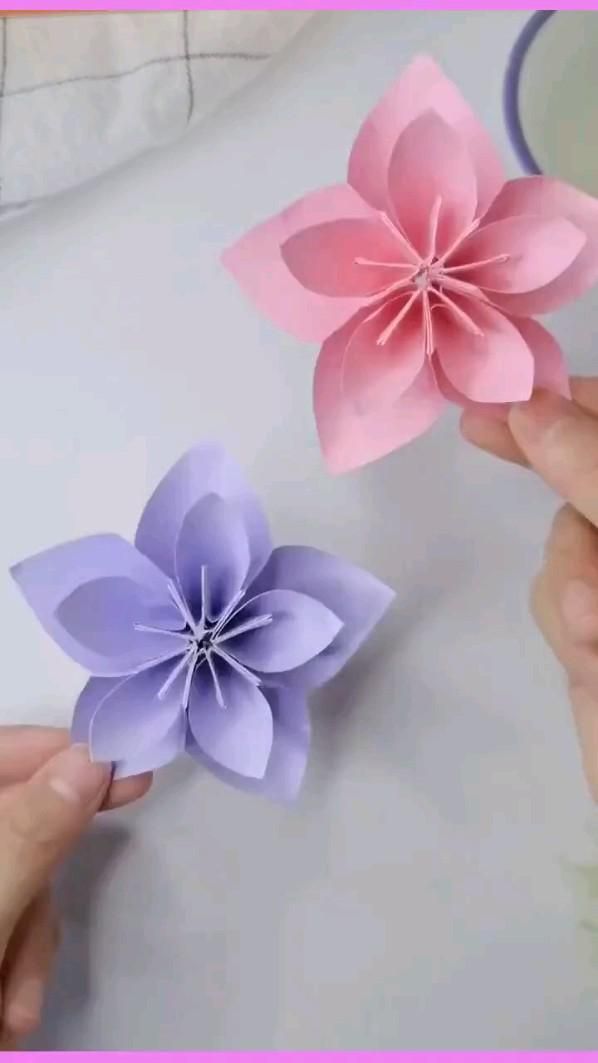 two paper flowers being held by someone's hands