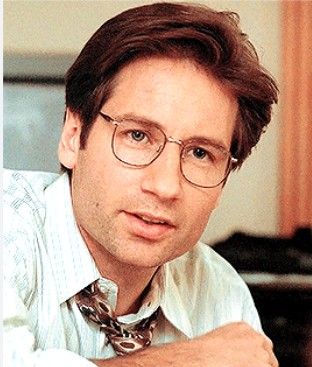 a man wearing glasses and a tie sitting at a desk