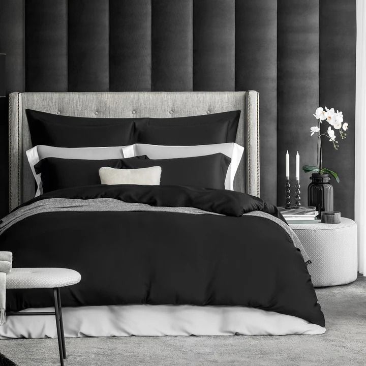 a black and white bedroom with an upholstered headboard, bedding, and pillows