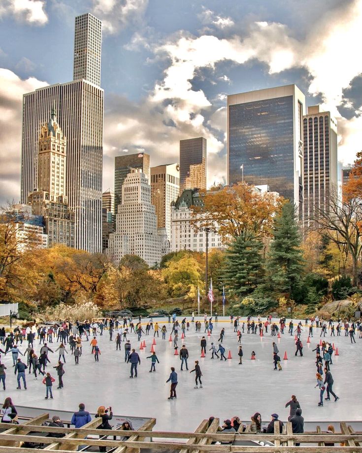 many people are skating on an ice rink in the middle of a city with tall buildings