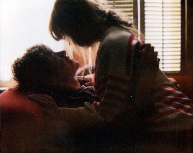 two people laying on a bed in front of a window