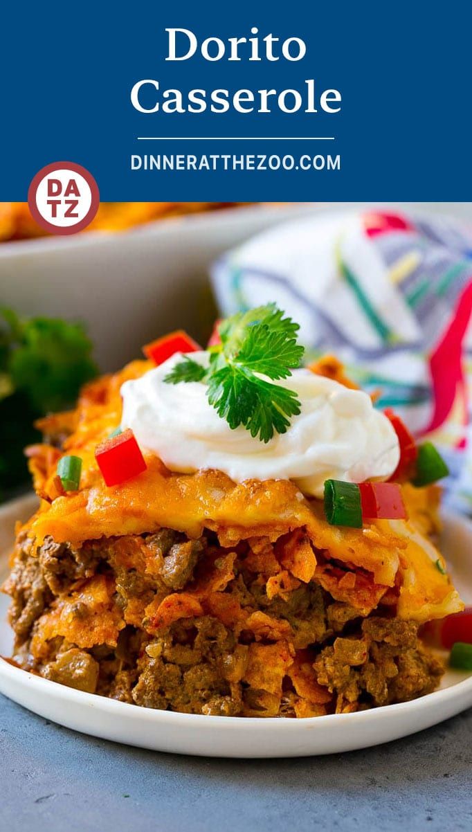 a white plate topped with layered mexican casserole next to a bowl of sour cream and cilantro