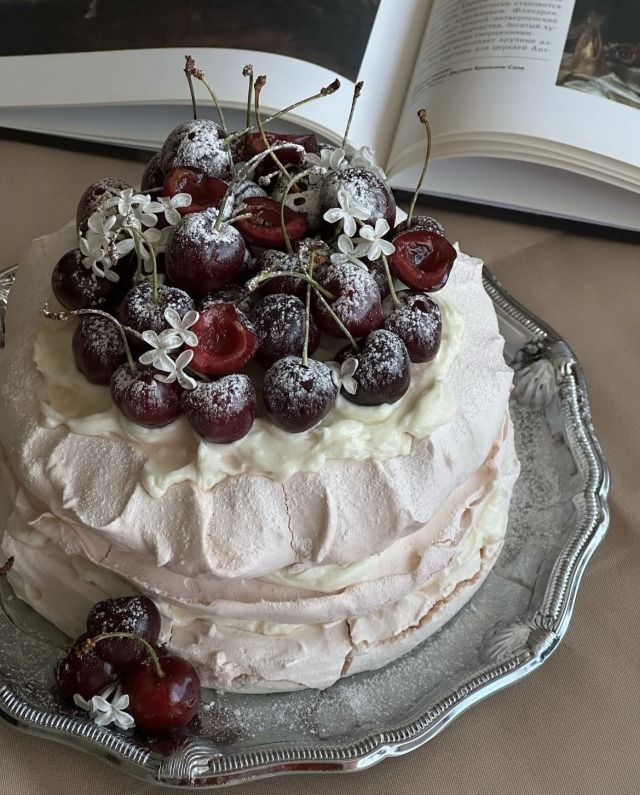 a cake with white frosting and cherries on top is sitting on a plate