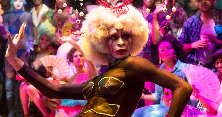 a group of people in costume and makeup on stage with clowns behind them at a circus