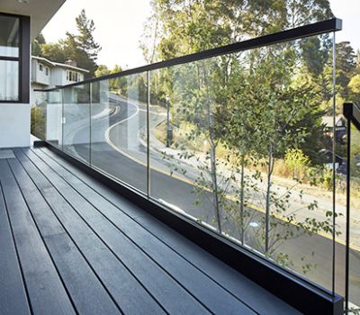 a balcony with glass railings and wood flooring