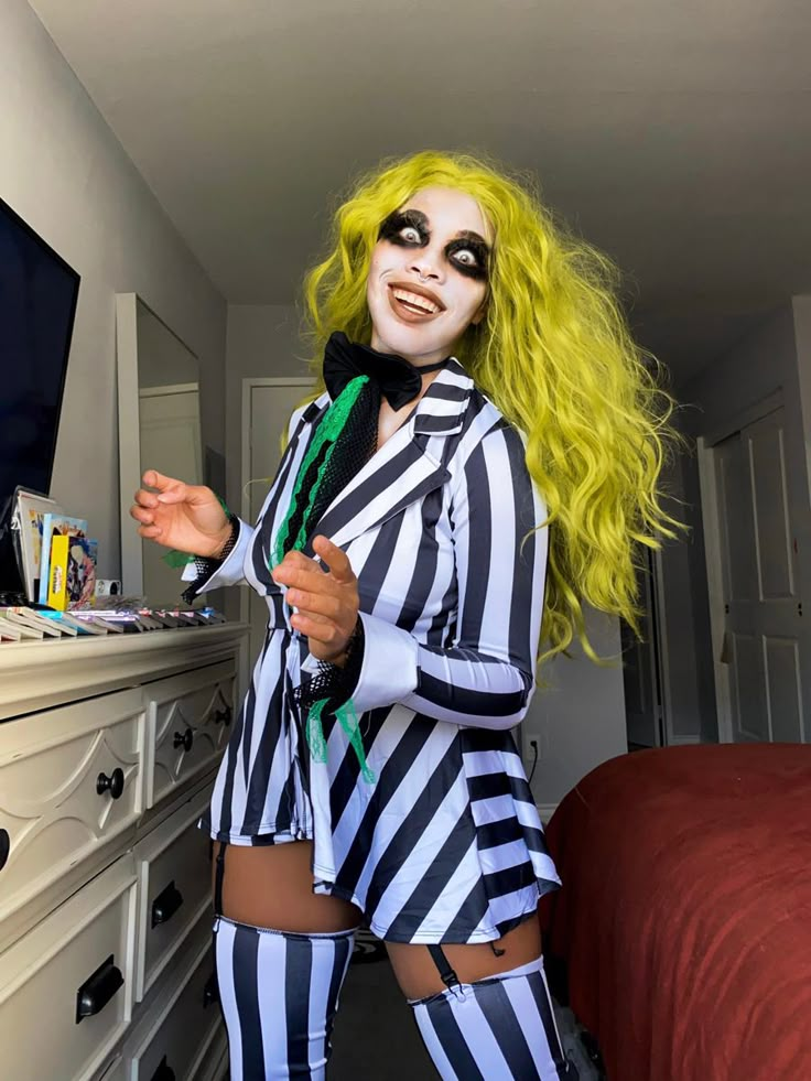 a woman dressed as beetlegirl standing in front of a dresser with makeup on her face