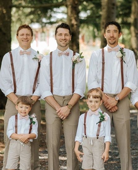 a group of men standing next to each other wearing suspenders and bow ties in front of trees