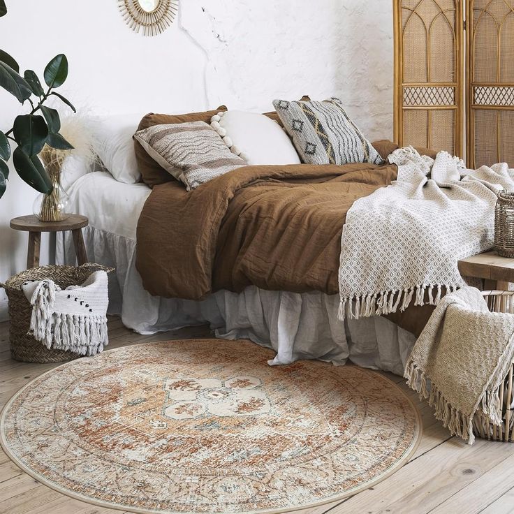 a bed with pillows and blankets on top of it in a room next to a potted plant