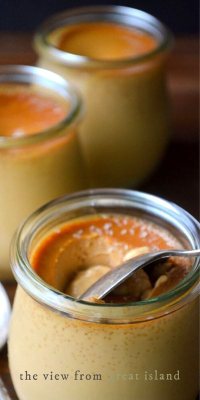 three jars filled with food sitting on top of a wooden table next to spoons