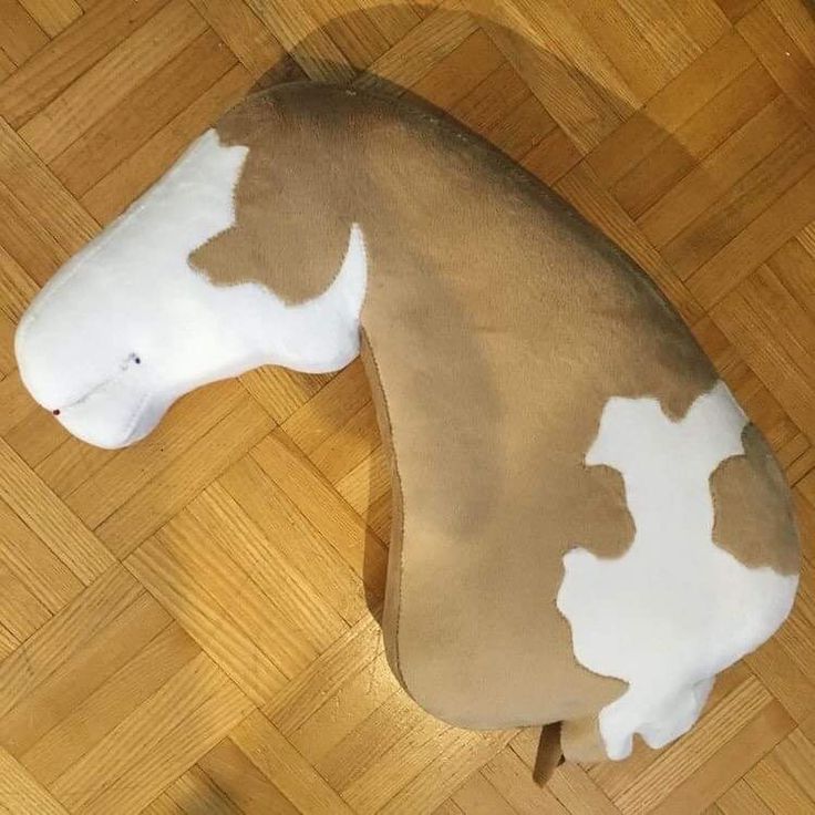 a stuffed horse laying on top of a hard wood floor covered in white and brown spots