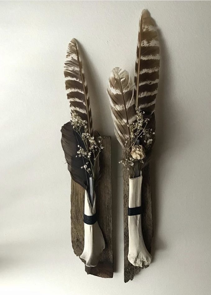 two antler heads with feathers and flowers on them are mounted to the wall in front of a white background