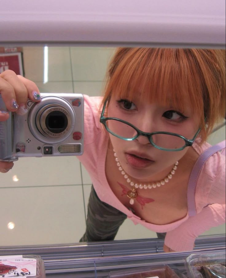 a young woman taking a selfie in front of a mirror with her camera attached to her neck